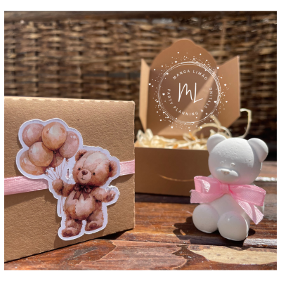 Caixa castanha com etiqueta de urso e balões ao lado de urso branco com laço rosa