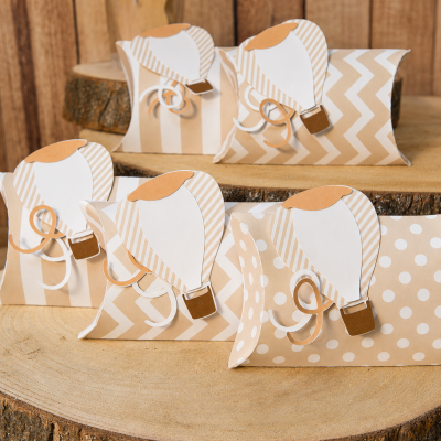 Caixas decorativas de papel bege com balões de ar quente em papel branco e bege sobre madeira