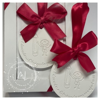 Etiqueta branca redonda com laço vermelho e gravura de lápis e boneco sorridente