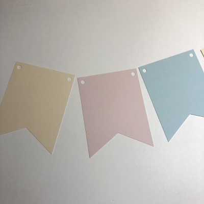 Bandeirolas de papel em tons pastel com orifícios para pendurar