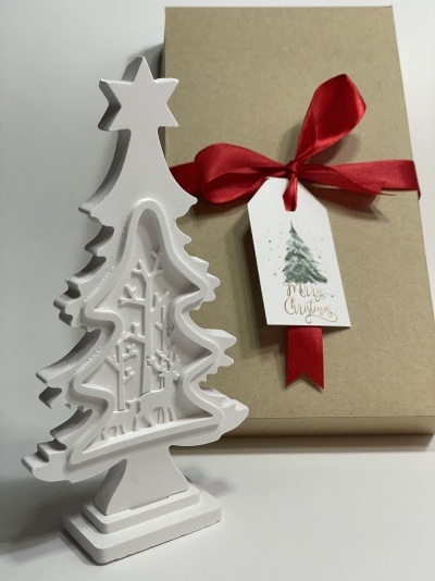 Decoração de Natal branca em forma de árvore com caixa de presente castanha e fita vermelha.