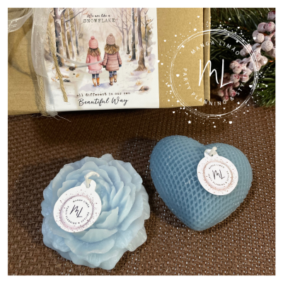 Duas velas decorativas azuis em forma de flor e coração com etiqueta da marca ML
