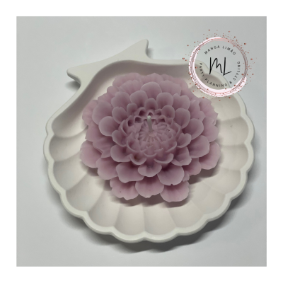 Vela flor lilás sobre base branca com forma de concha e golfinho, fundo branco.