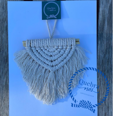 Pendente macramê bege claro com franjas em fundo branco e autocolante verde