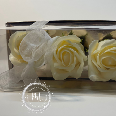 Três rosas creme em caixa transparente com fita branca e selo MANGA LIMÃO PLANNING & DESIGN