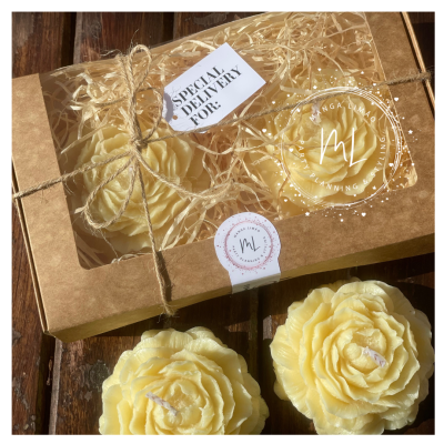 Velas em formato de rosa amarelas em caixa de cartão com tampa transparente e etiqueta