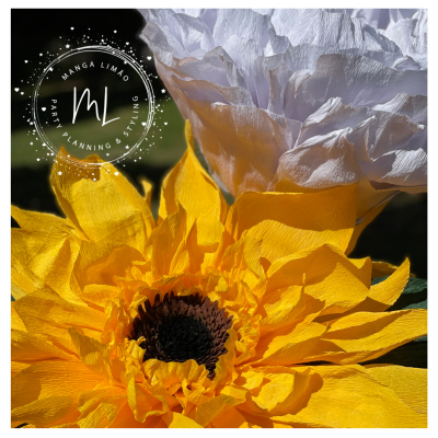 Duas flores de papel, uma amarela e outra branca, com selo circular MANGA LIMÃO PARTY PLANNING STYLING