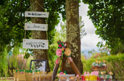 Placas decorativas penduradas numa árvore com textos em inglês e decoração de festa exterior