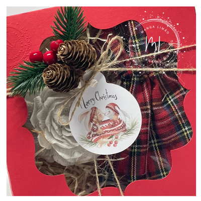 Conjunto de decoração natalícia com pinhas, flor branca e laço xadrez em caixa vermelha