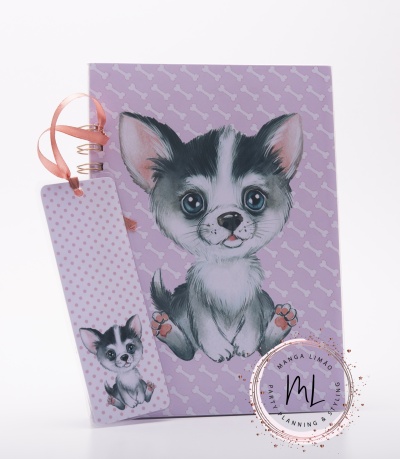 Caderno lilás com padrão de ossos e desenho de cão e marcador de páginas com fita cor de rosa