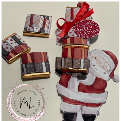 Quadrados de chocolate embrulhados sobre ilustração do Pai Natal e etiqueta de Natal