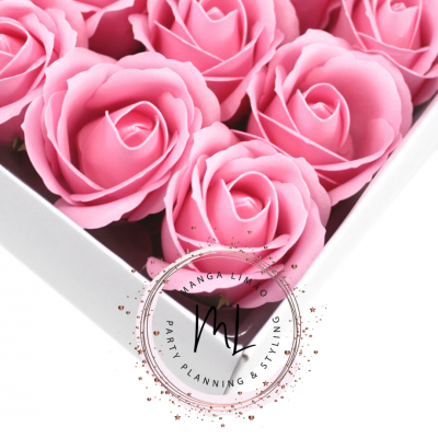 Caixa branca com flores artificiais rosa claro organizadas em fileiras.