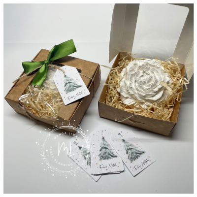 Caixas de presente em cartão castanho e flor decorativa branca com etiquetas de Natal.
