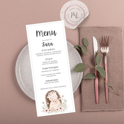 Menu impresso sobre prato com talheres e guardanapo em fundo rosa.
