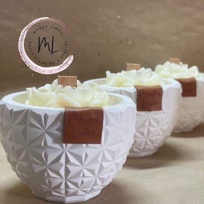 Três velas aromáticas em recipientes brancos com textura geométrica.