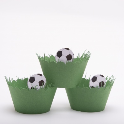 Forminhas verdes com relva e bolas de futebol em miniatura