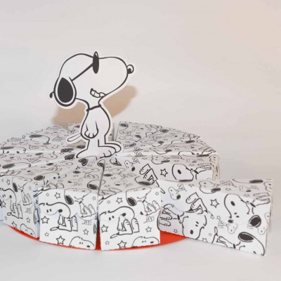 Doces embalados com estampas Snoopy organizados como fatias de bolo com figura de Snoopy grande em cartão