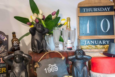 Estátuas de macacos, tulipas, garrafas, bolo vermelho e calendário de madeira azul indicando quinta-feira 10 de janeiro.