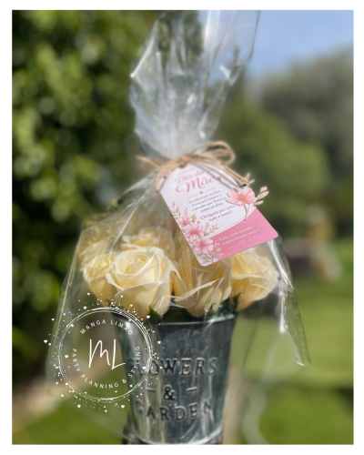 Vaso metálico com flores artificiais amarelas e cartão rosa em embalagem plástica