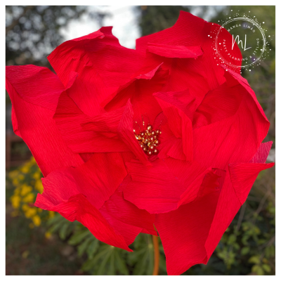 Flor decorativa de papel crepom vermelha com centro dourado ao ar livre