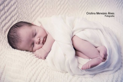 Bebé recém-nascido dormindo envolto em cobertor branco de malha