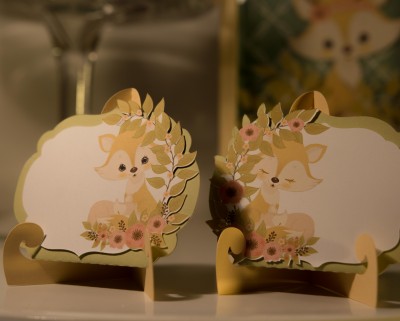Dois marcadores de lugar de papel com desenho de veado e flores, com suporte dourado