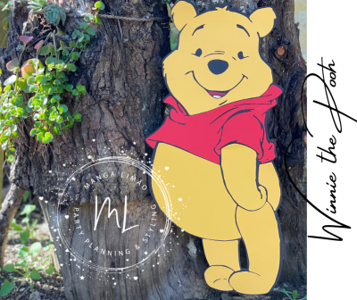 Recorte Winnie the Pooh amarelo com camisola vermelha afixado num tronco de árvore