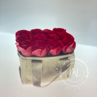 Arranjo de flores artificiais vermelhas em caixa de tecido bege com alças