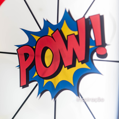 Adesivo estilo banda desenhada com texto POW! vermelho em fundo amarelo e azul sobre superfície branca