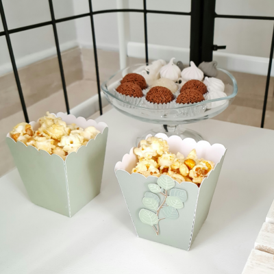 Recipientes verdes com pipocas e prato de doces em vidro