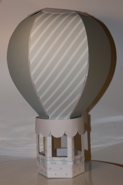 Modelo decorativo de balão de ar quente em papel com riscas verdes e base branca com pontos