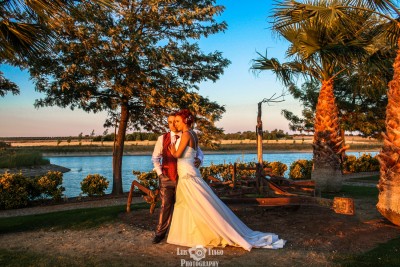 Casal de noivos ao ar livre junto a um lago ao pôr do sol