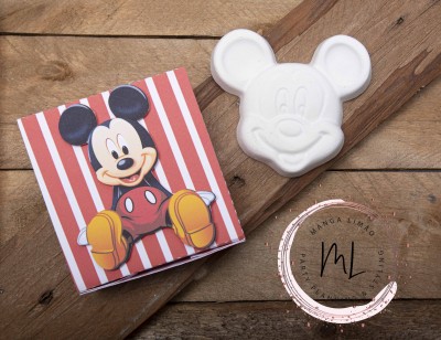 Sabonete Mickey Mouse branco ao lado da embalagem com imagem do personagem e selo MANGA LIMÃO numa superfície de madeira.