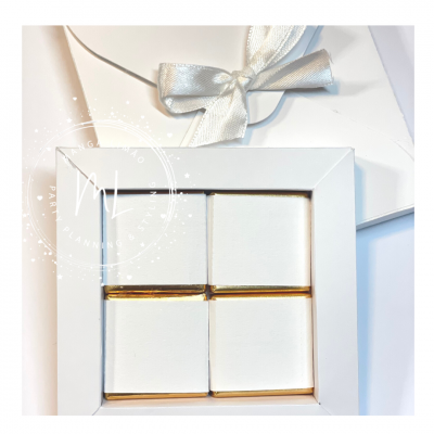 Caixa branca com chocolates embrulhados e embalagem com laço prateado