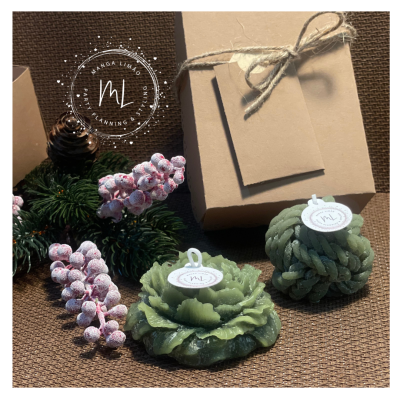 Duas velas verdes decorativas em forma de flor com etiquetas ML, embalagem castanha com laço e decoração natalícia