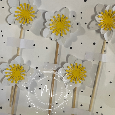 flores decorativas de papel branco e amarelo em palitos de madeira com fundo branco e pontos pretos