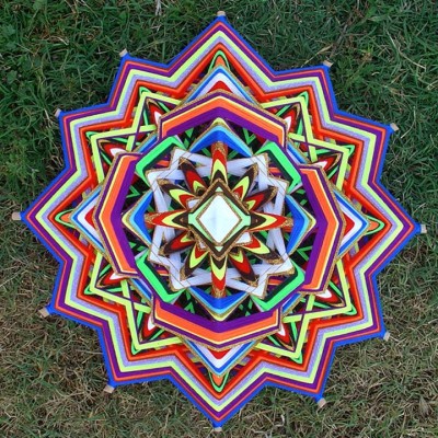 Mandala colorida de lã com espelho ao centro sobre relva verde