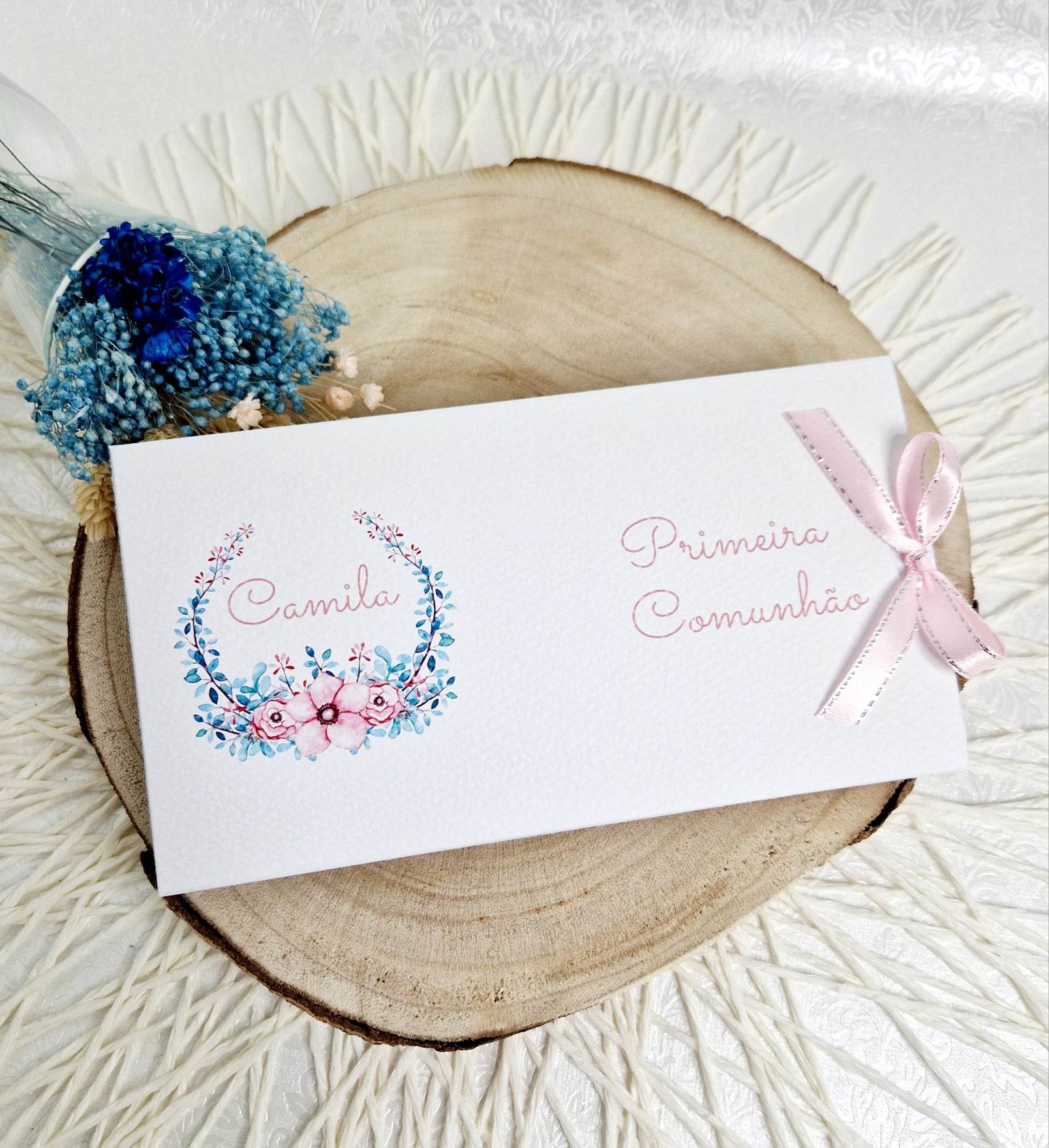 Convite floral menina Convite branco decorado com flores e laço rosa sobre base de madeira com flores secas ao lado