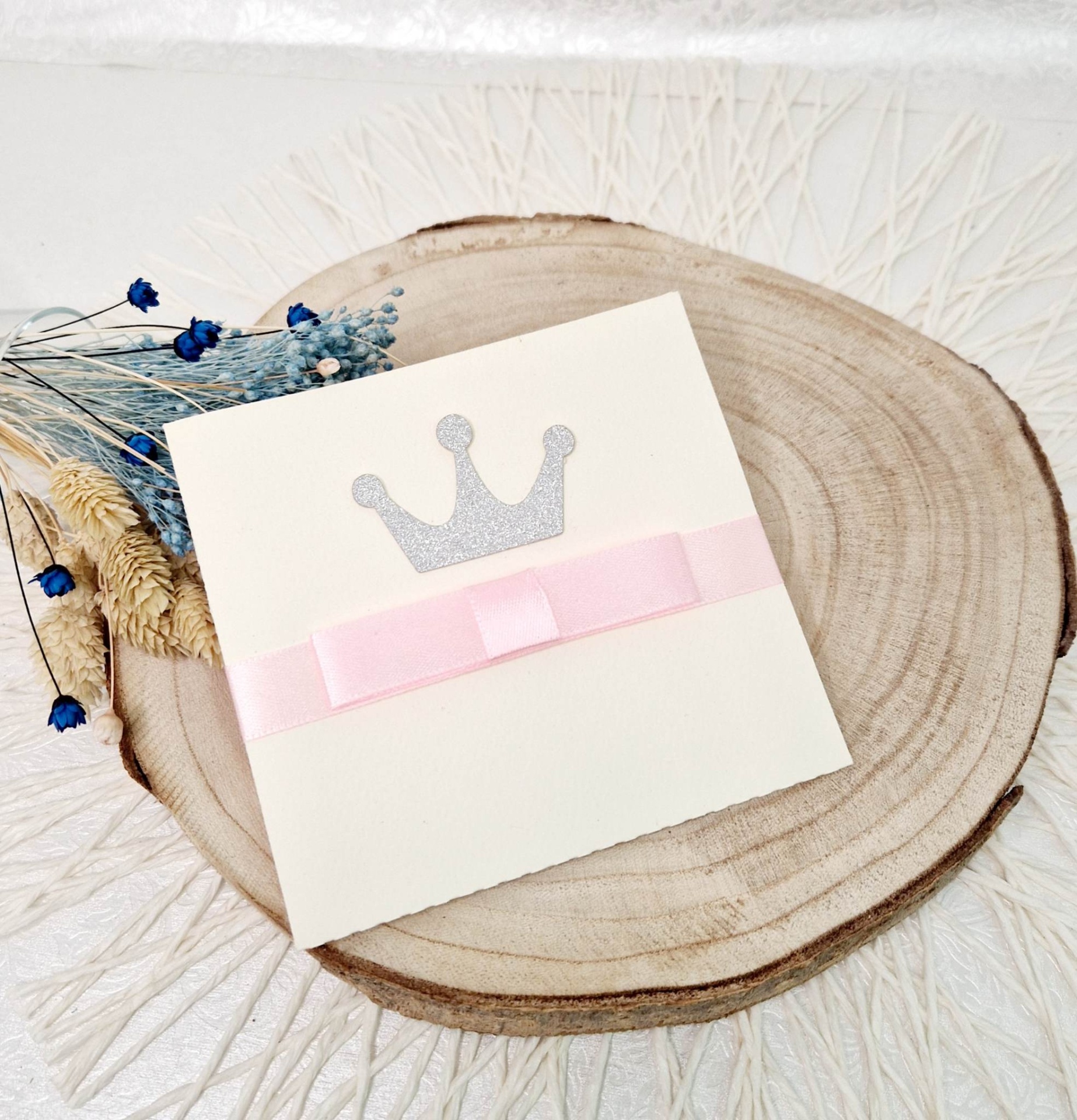 convite coroa menina Convite branco com coroa prateada e fita rosa sobre base de madeira com flores secas