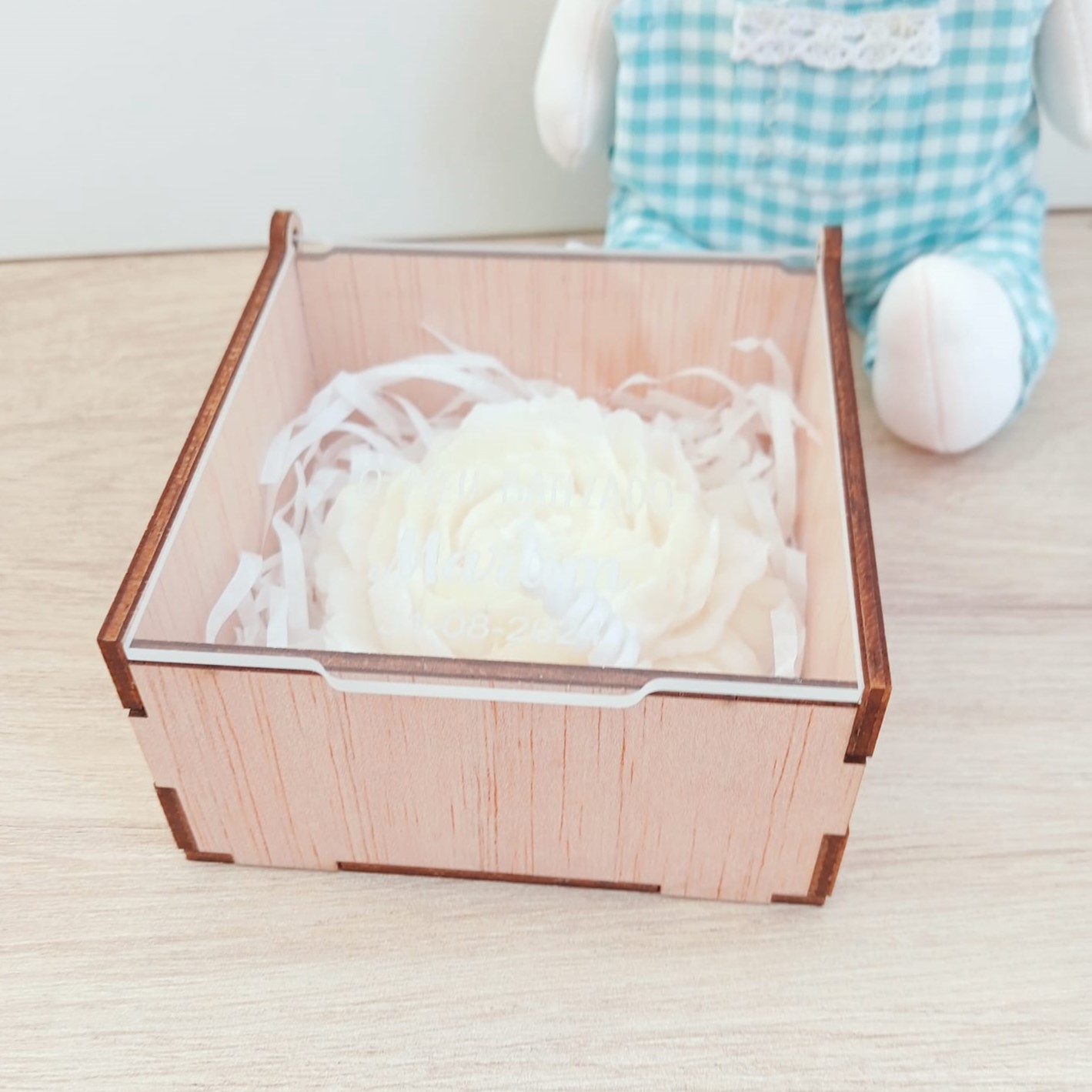 Caixa e Vela Flor Artesanal caixa de madeira clara com flor branca de tecido e papel branco rasgado sobre mesa clara