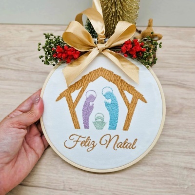 Bastidor de Natal bordado com presépio e laço dourado com flores vermelhas