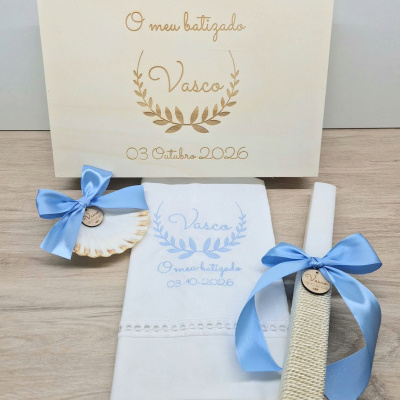 Conjunto para batizado com decoração personalizada em azul e madeira sobre superfície de madeira clara.
