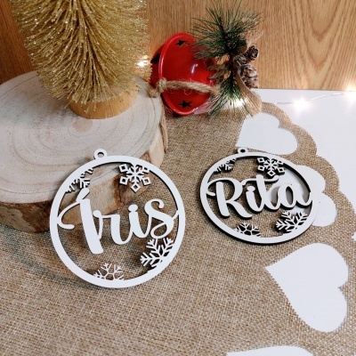 Ornamentos de natal de madeira com nomes Iris e Rita sobre tecido bege com corações e decoração natalina