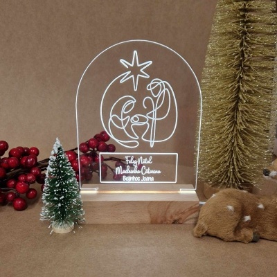 Placa de acrílico iluminada com desenho natalício sobre suporte de madeira entre enfeites de Natal