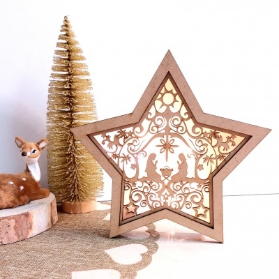 Estrela de madeira iluminada com cena da Natividade, junto a árvore de Natal dourada e veado de decoração