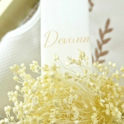 Vaso branco com planta seca amarela e texto 'Devann'