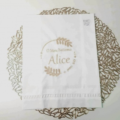 Guardanapo branco bordado com texto de batismo e suporte decorativo dourado