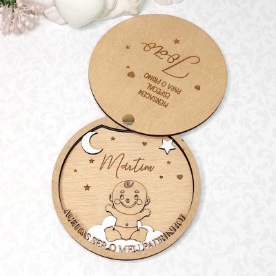 Caixa redonda em madeira gravada com desenho de bebé e textos, sobre superfície branca com padrão floral