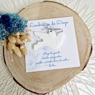 Cartão branco com pendente em forma de anjo sobre base de madeira redonda e flores secas