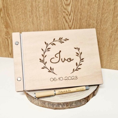 Livro de madeira clara personalizado com nome Ivo e data, com caneta gravada, sobre tábua redonda de madeira